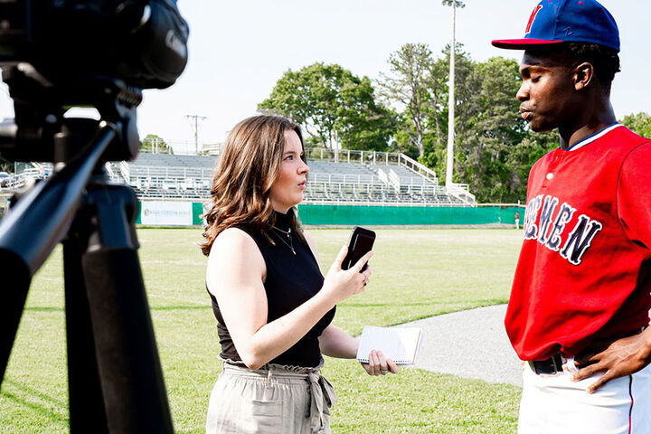 A student reporter interviews a baseball player.